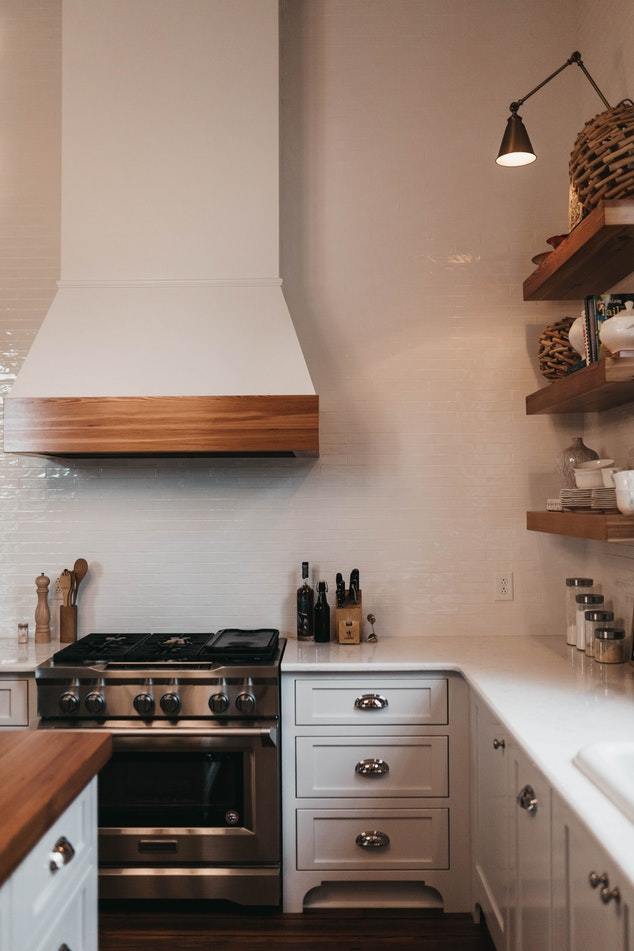 Lots of white and lots of nice wood trim completes this farmhouse kitchen decor. Open shelves stocked with plates and cups gives an old time throwback look.